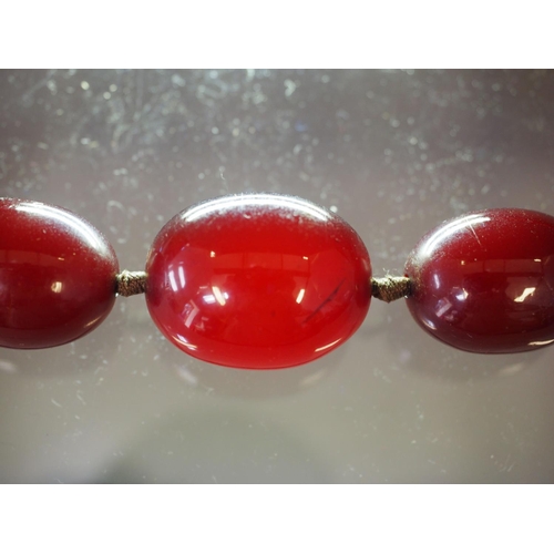 368 - An Art Deco cherry amber Bakelite graduated bead necklace, the largest oval bead 22mm wide, total we... 