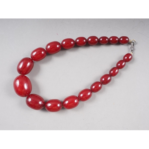 371 - An Art Deco cherry amber Bakelite graduated bead necklace, the largest oval bead 20mm wide, total we... 