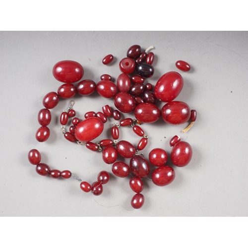 374 - A number of loose Art Deco cherry amber Bakelite beads, the largest 21mm wide, total weight 132.1g