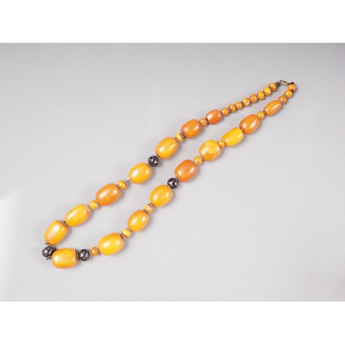 375 - An Art Deco butterscotch/egg yolk amber necklace with white metal and horn spacers, the largest barr... 