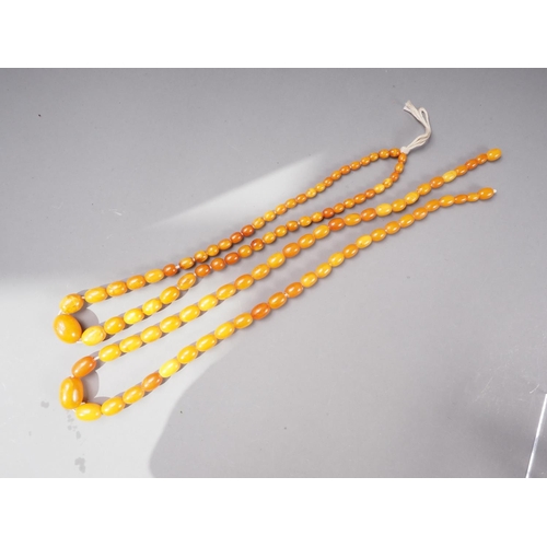 379 - An Art Deco butterscotch/egg yolk graduated bead necklace, the largest oval bead 11mm wide, and anot... 