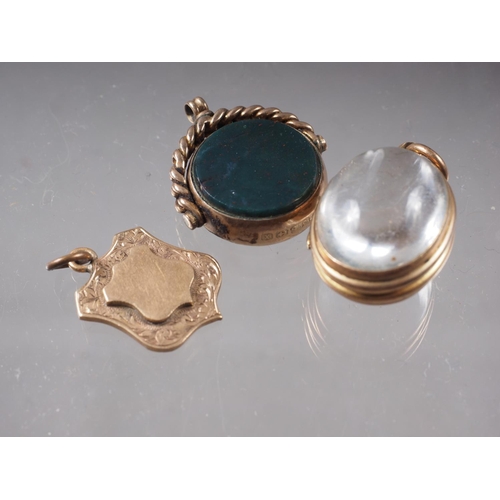 431 - A 9ct gold fob spinner, mounted bloodstone and a compass, a yellow metal and rock crystal locket (ch... 