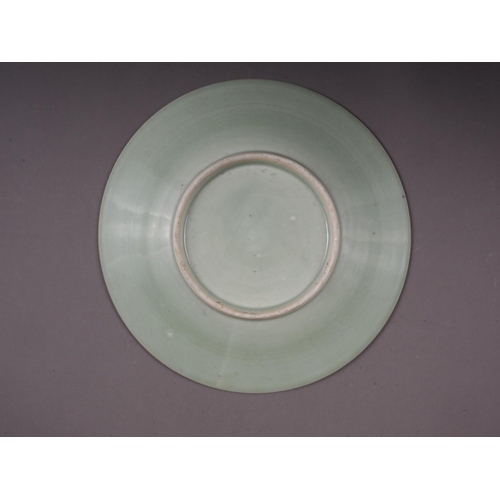 86 - A Chinese celadon glazed plate with incised floral and scrolled decoration, 11 1/2