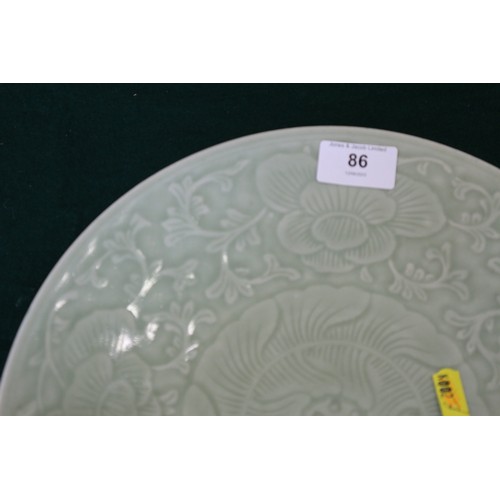 86 - A Chinese celadon glazed plate with incised floral and scrolled decoration, 11 1/2