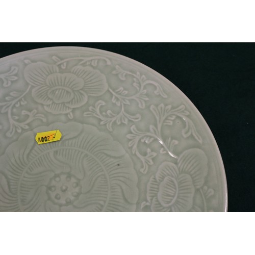 86 - A Chinese celadon glazed plate with incised floral and scrolled decoration, 11 1/2