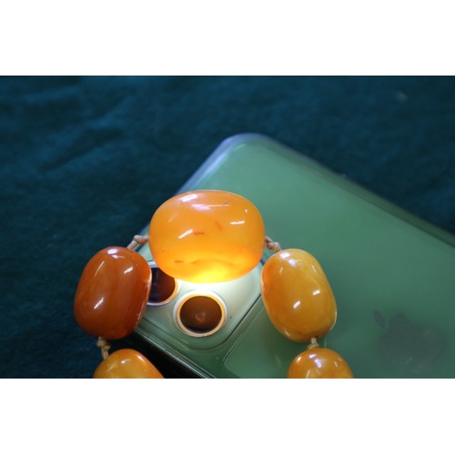 367 - An Art Deco butterscotch/egg yolk amber graduated bead necklace, the largest oval bead 19mm wide, to... 