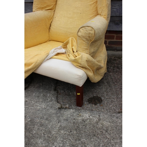 609 - A wing armchair of Georgian design, with down loose seat cushions and yellow loose covers, on square... 