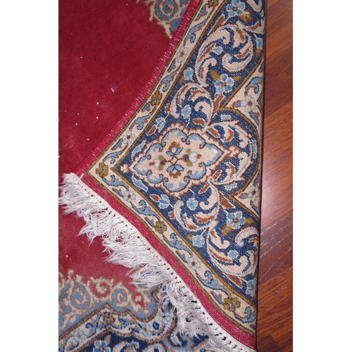 677 - A Persian city rug with scroll design on a red ground and multi-borders, in shades of black, cream a... 