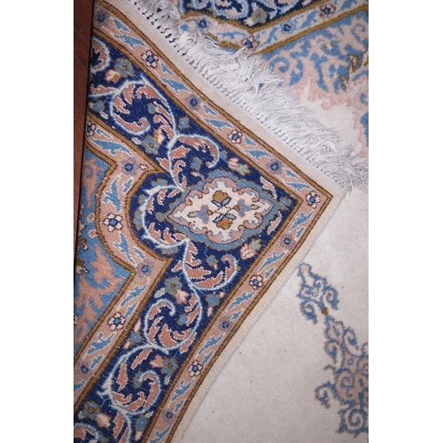 678 - A Persian city rug with central scroll design on a cream ground and scroll borders in shades of blue... 