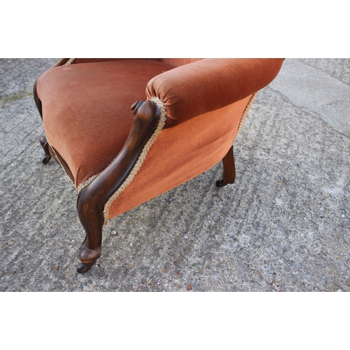 492 - A Victorian carved walnut showframe armchair, upholstered in a rust velour, on cabriole supports