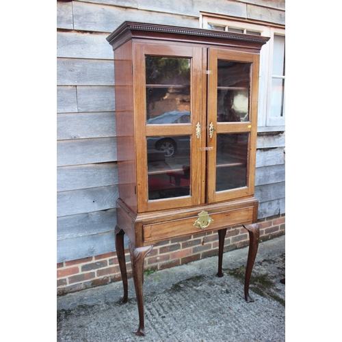 579 - An early 20th century walnut display cabinet/bookcase, the upper section enclosed two glazed doors o... 