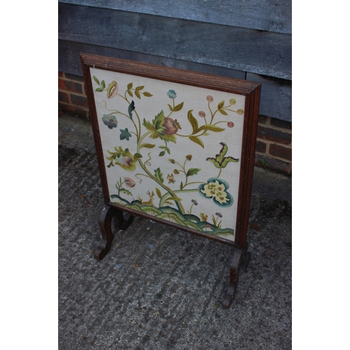 584 - An early 20th century walnut framed firescreen with crewelwork panel end splay supports, 20