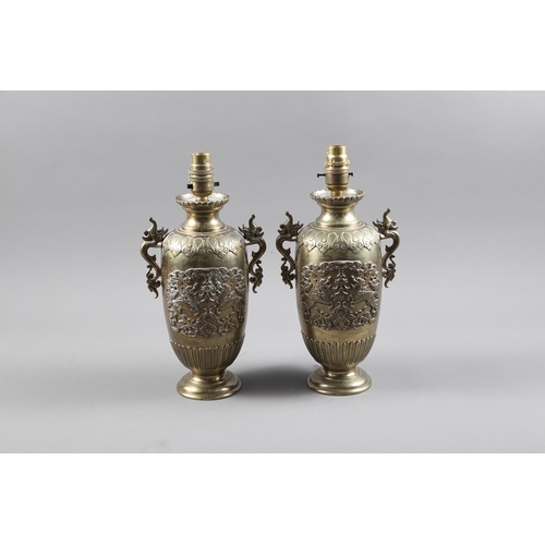 310 - A pair of Japanese brass table lamps with mythical beast decoration and handles, on circular bases, ... 