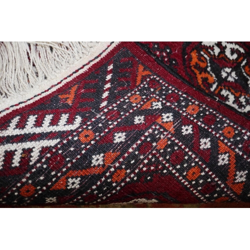 688 - A Bokhara rug with fourteen guls on a plum ground and multi-bordered in shades of black, orange and ... 