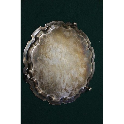 345 - A silver piecrust edge salver, on three scrolled supports, 8