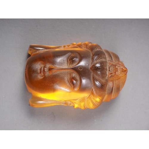 65 - An Oriental carved amber bust of Buddha, partial signature to reverse, 1 3/4