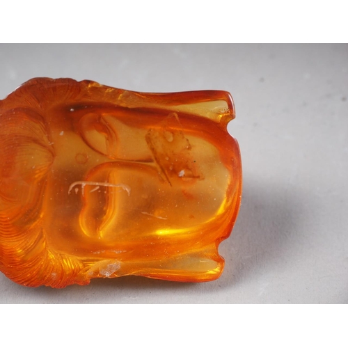 65 - An Oriental carved amber bust of Buddha, partial signature to reverse, 1 3/4