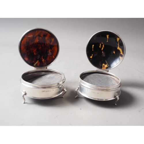 269 - A pair of circular silver and tortoiseshell dressing table hinged boxes, on three cabriole supports,... 