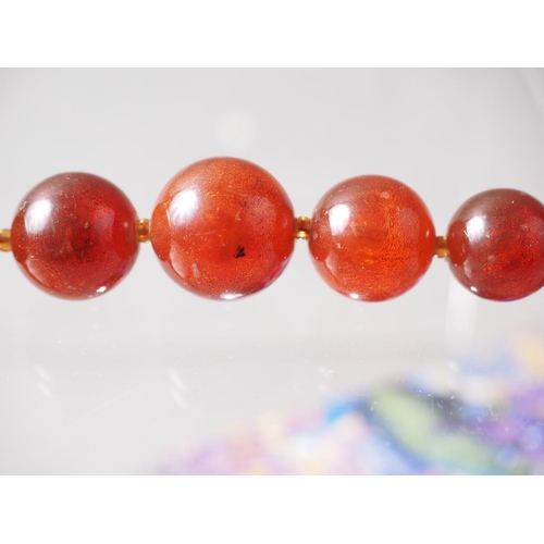 291 - A coral coloured amber Bakelite bead necklace, the largest oval bead, 19mm long, 66.3g gross, and a ... 