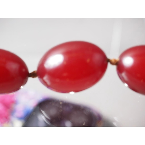 301 - A cherry amber Bakelite bead necklace, the largest oval bead, 27mm long, 68.5g gross