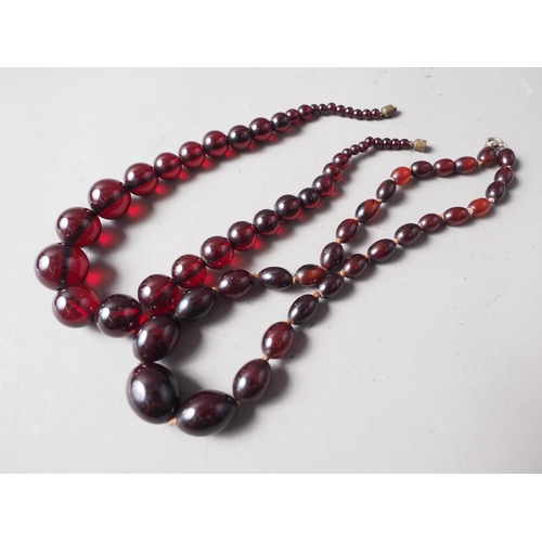 304 - A cherry amber Bakelite round bead necklace, the largest bead, 20mm dia, 42.2g gross, and a similar ... 