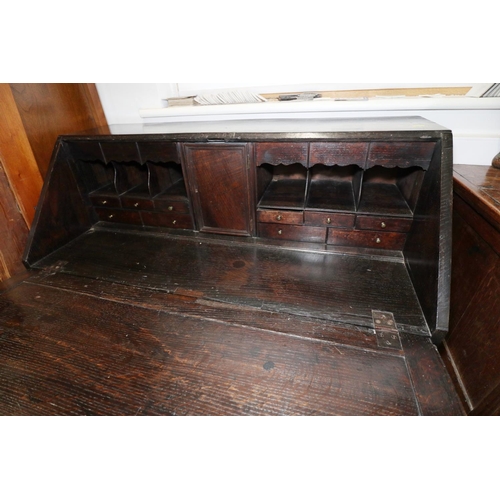 410 - A 19th century carved oak fall front bureau, the interior fitted drawers and pigeonholes, over two d... 