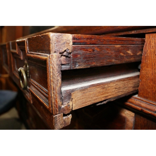 424 - An early 18th century oak chest of four long drawers with fielded panel fronts and ring handles, on ... 