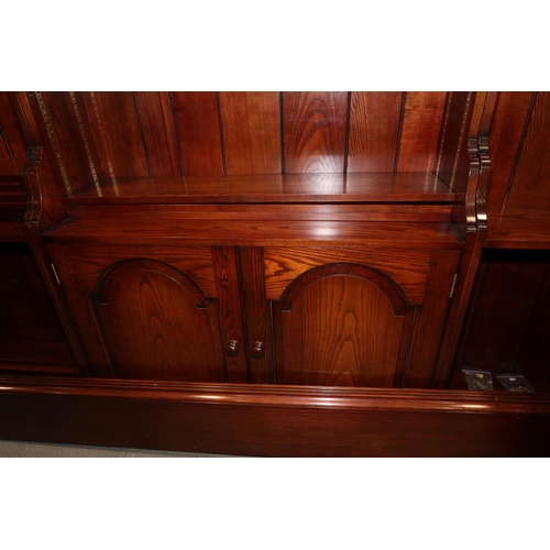 461 - An oak three-section open bookcase, the centre section enclosed two panelled doors with flanking ope... 