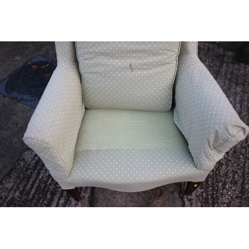 451 - An Edwardian low seat wing back armchair, upholstered in a light green fabric