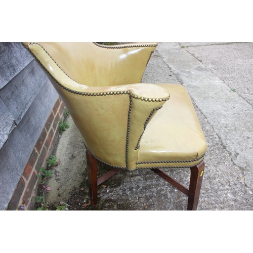 490 - A studded armchair, upholstered in a mustard leather, on stained as walnut cross stretchered support... 