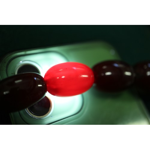 300 - A cherry amber Bakelite bead necklace, the largest oval bead, 29mm long, 64.4g gross