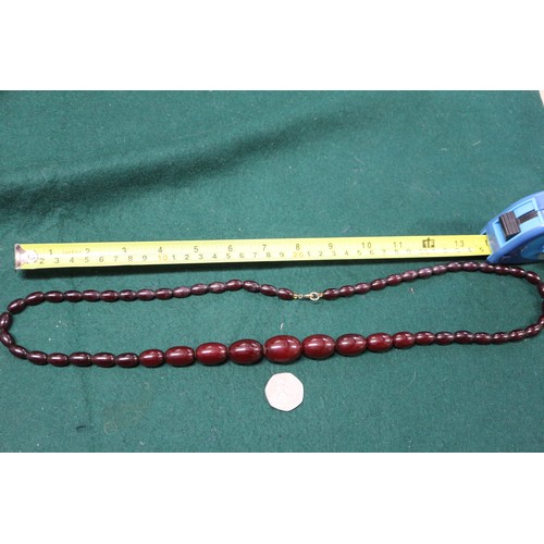 300 - A cherry amber Bakelite bead necklace, the largest oval bead, 29mm long, 64.4g gross