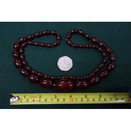 302 - A cherry amber Bakelite bead necklace, the largest oval bead, 34mm long, 71.6g gross, and another si... 