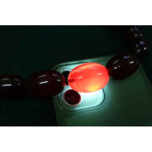 302 - A cherry amber Bakelite bead necklace, the largest oval bead, 34mm long, 71.6g gross, and another si... 