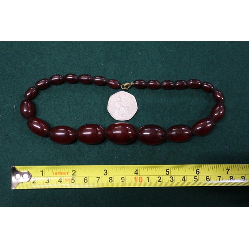 302 - A cherry amber Bakelite bead necklace, the largest oval bead, 34mm long, 71.6g gross, and another si... 