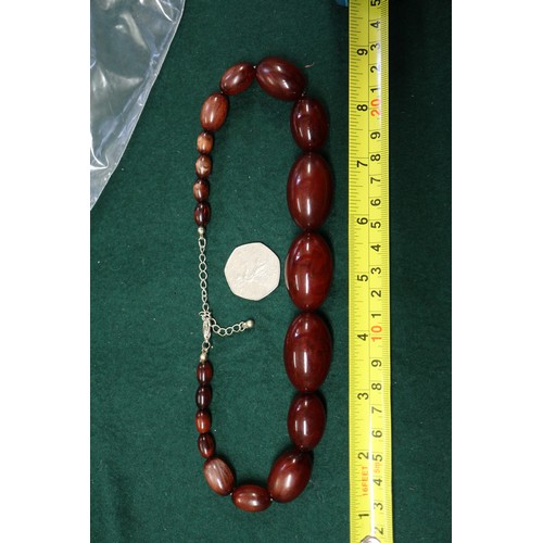 303 - A cherry amber Bakelite bead necklace, the largest oval bead, 37mm long, 61.8g gross and another sim... 