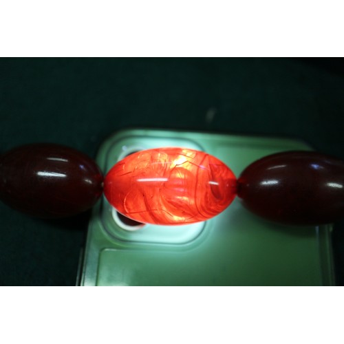 303 - A cherry amber Bakelite bead necklace, the largest oval bead, 37mm long, 61.8g gross and another sim... 