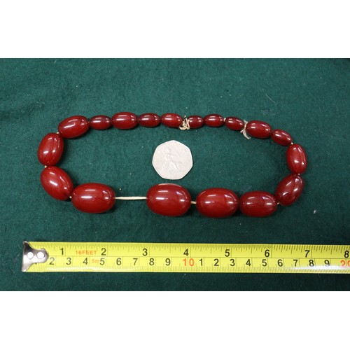 303 - A cherry amber Bakelite bead necklace, the largest oval bead, 37mm long, 61.8g gross and another sim... 