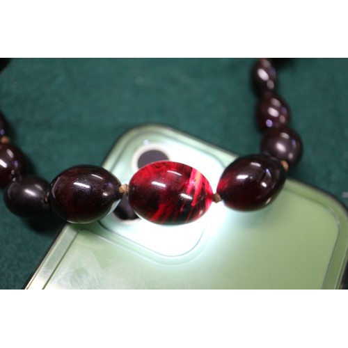 304 - A cherry amber Bakelite round bead necklace, the largest bead, 20mm dia, 42.2g gross, and a similar ... 