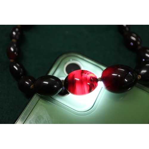 304 - A cherry amber Bakelite round bead necklace, the largest bead, 20mm dia, 42.2g gross, and a similar ... 