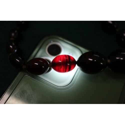 304 - A cherry amber Bakelite round bead necklace, the largest bead, 20mm dia, 42.2g gross, and a similar ... 