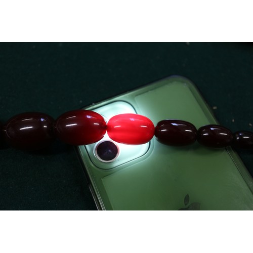 300 - A cherry amber Bakelite bead necklace, the largest oval bead, 29mm long, 64.4g gross