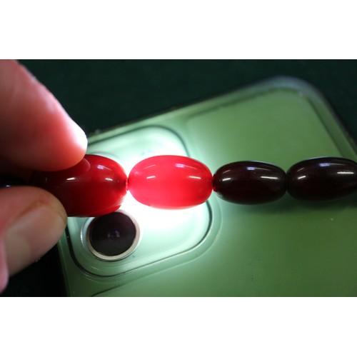 300 - A cherry amber Bakelite bead necklace, the largest oval bead, 29mm long, 64.4g gross