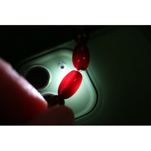 300 - A cherry amber Bakelite bead necklace, the largest oval bead, 29mm long, 64.4g gross