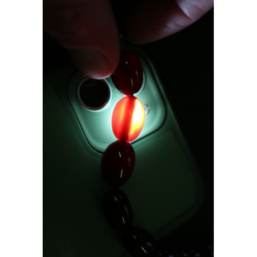 300 - A cherry amber Bakelite bead necklace, the largest oval bead, 29mm long, 64.4g gross