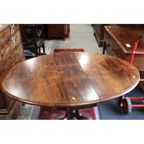 425 - A 19th century rosewood oval drop leaf table, on folding quadruple scroll supports, 36