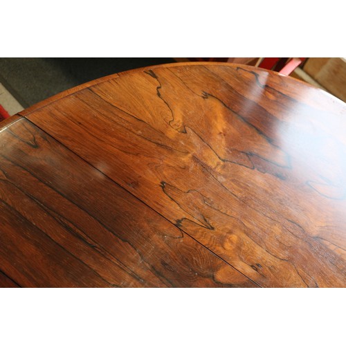 425 - A 19th century rosewood oval drop leaf table, on folding quadruple scroll supports, 36