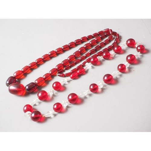 188 - A cherry amber Bakelite bead necklace, the largest barrel shaped bead, 30mm long, 80.8g gross, and a... 