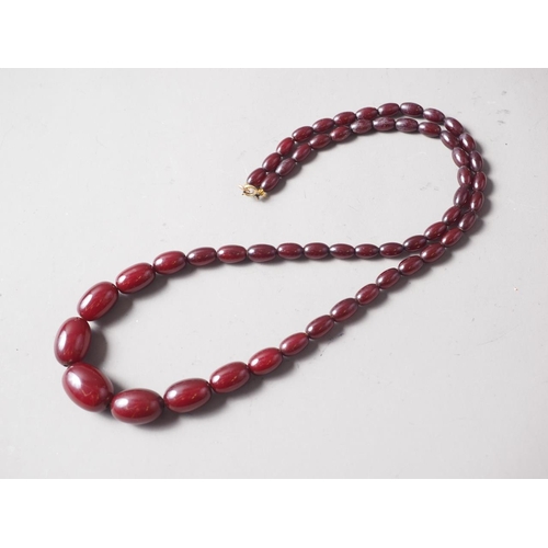 189 - A cherry amber Bakelite bead necklace, the largest oval bead, 29mm long, 64.4g gross