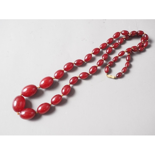 190 - A cherry amber Bakelite bead necklace, the largest oval bead, 27mm long, 68.5g gross